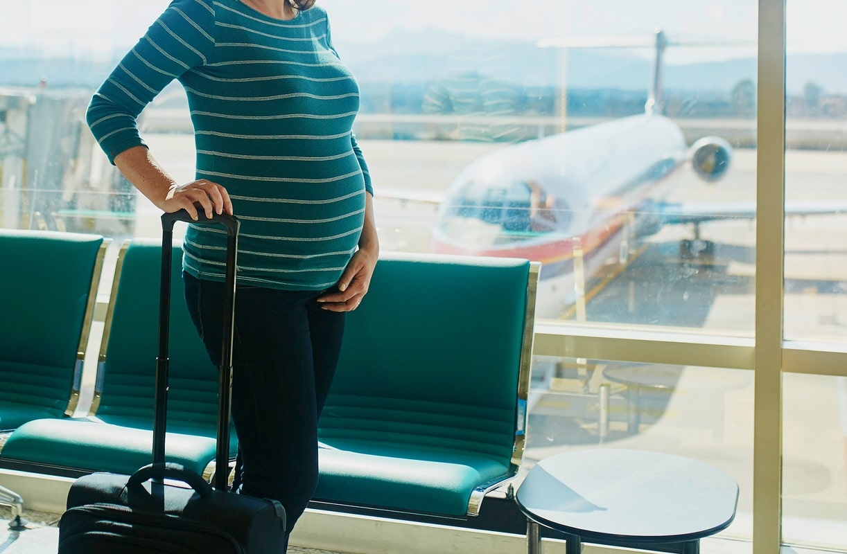 femme enceinte avec une valise qui va prendre l'avion